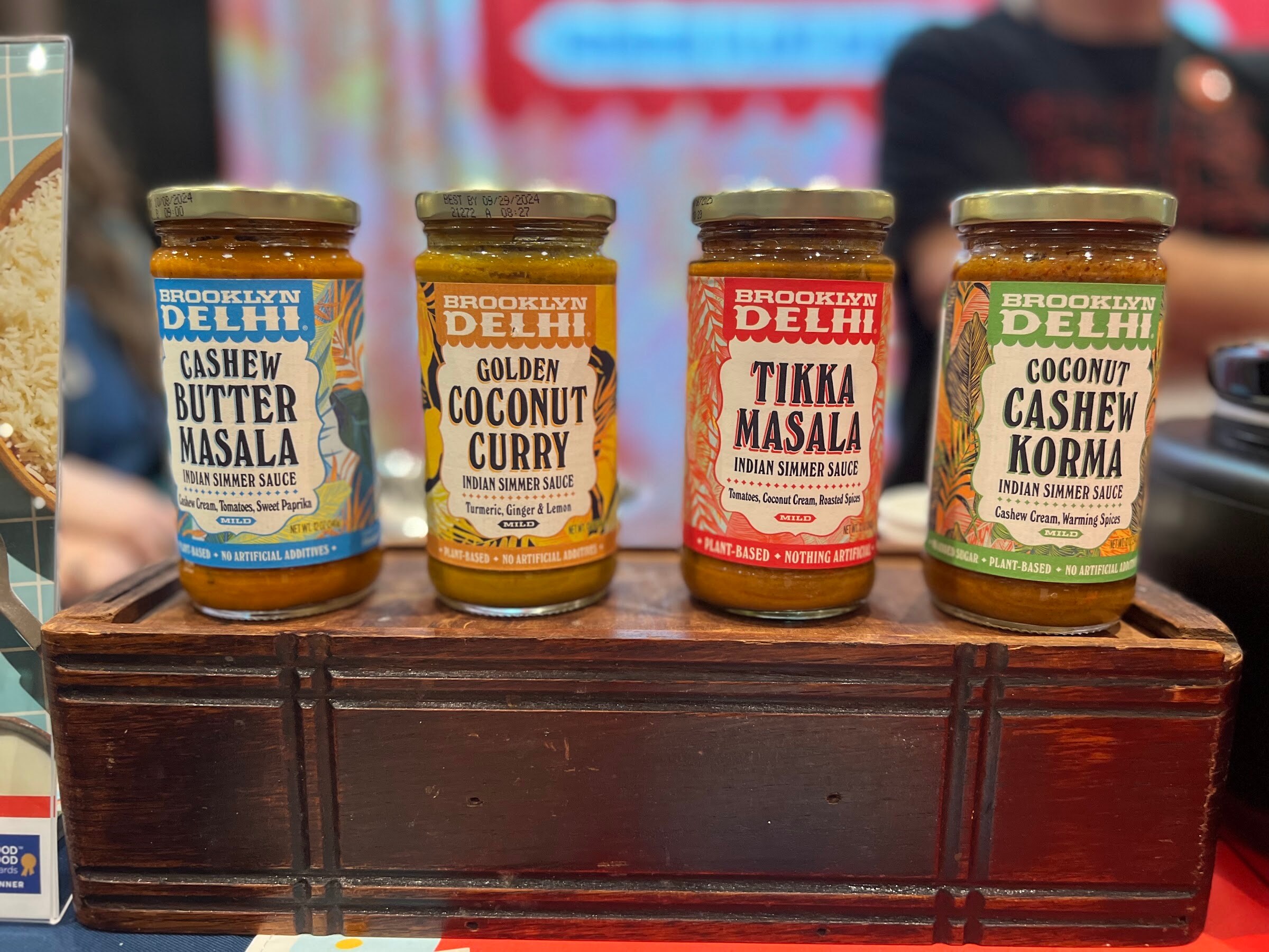 Jars of Brooklyn Delhi Cashew Butter Masala, Golden Coconut Curry, Tikka Masala and Coconut Cashew Korma stand on a wooden riser