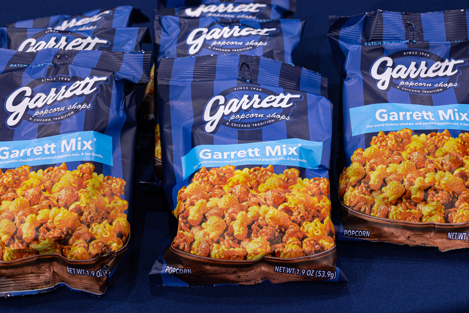 Stacked blue striped Garrett Popcorn Shops Garrett Mix bags filled with caramel and cheese popcorn