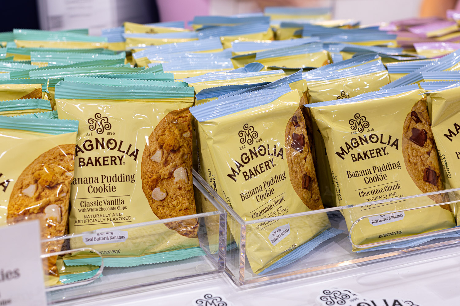 Individually wrapped Magnolia Bakery cookies, including Banana Pudding and Classic Vanilla flavors, sit in a clear acrylic tray