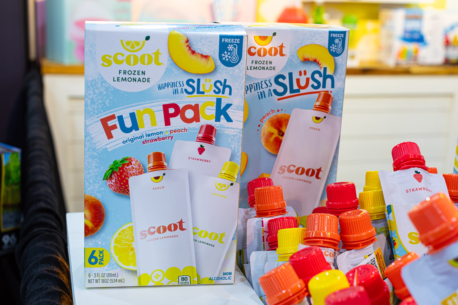 Scoot Slush Fun Pack boxes in peach and strawberry lemonade stand behind pouches with orange caps