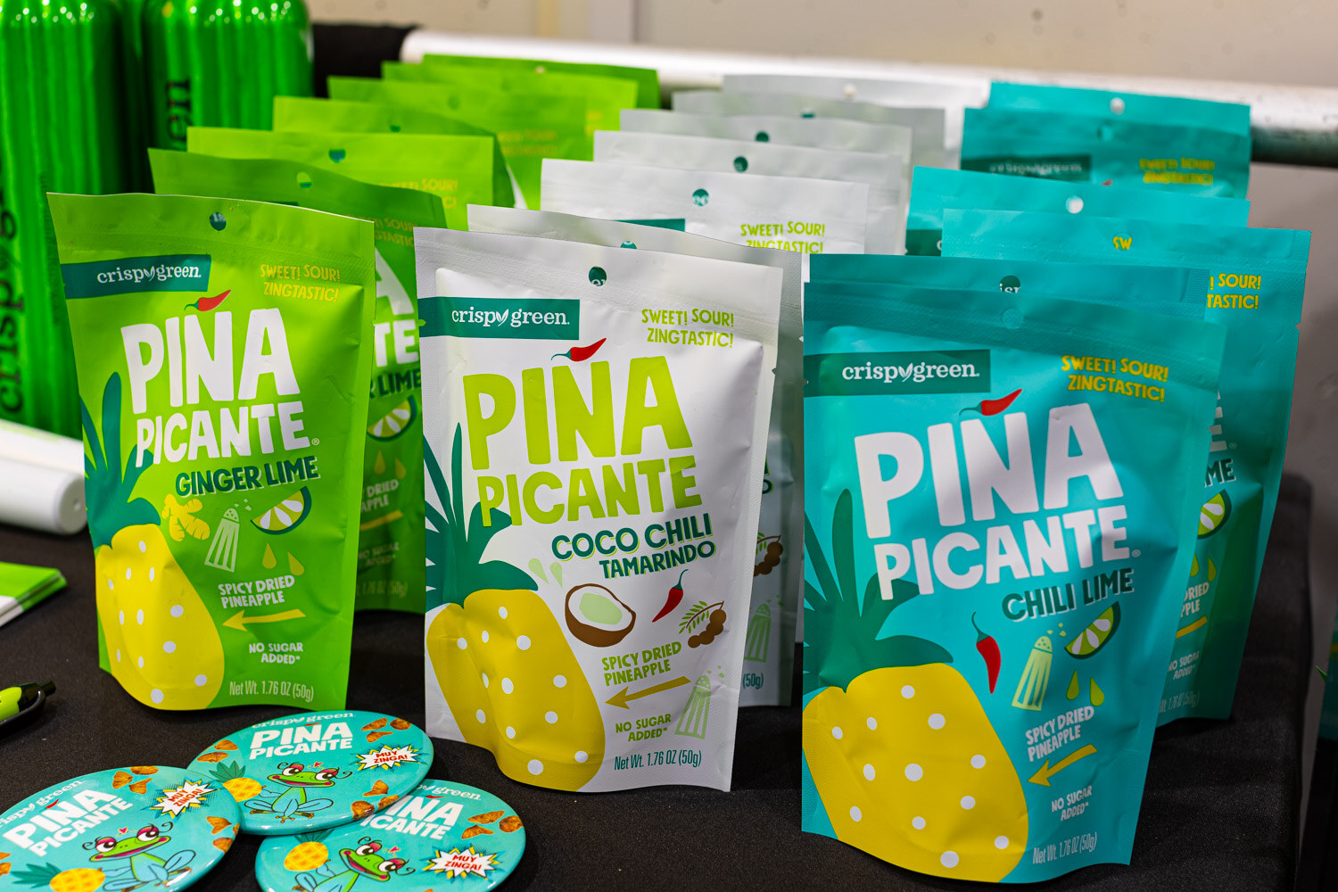 Teal and green pouches of Crispy Green Pina Picante freeze-dried pineapple in ginger lime, coco chili and chili lime flavors