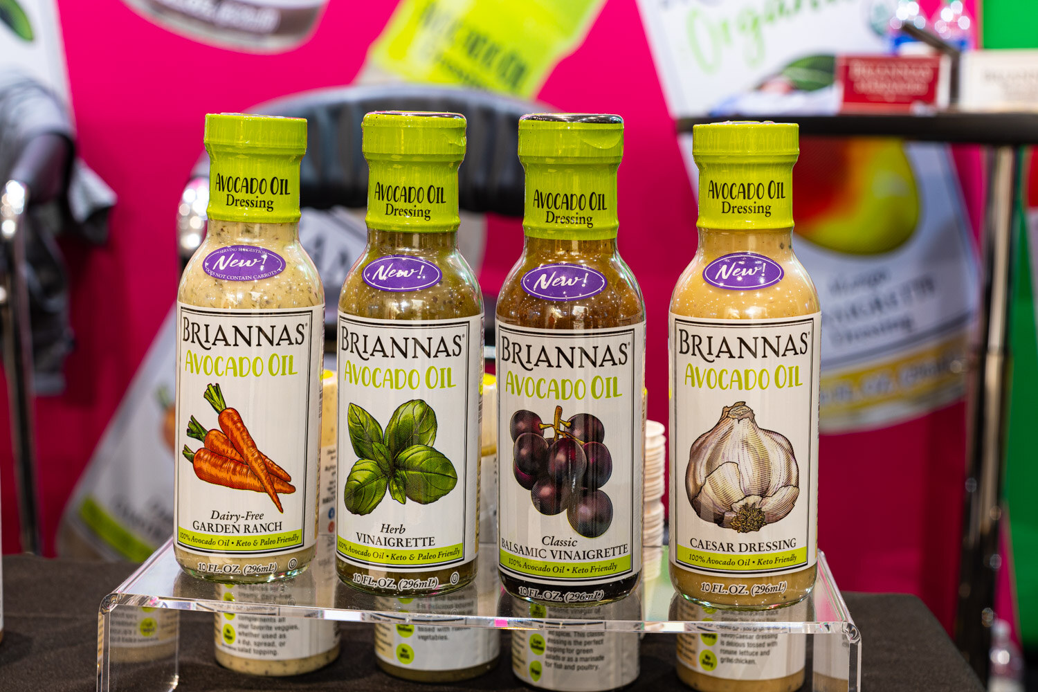 Four bottles of Briannas Avocado Oil dressings in garden ranch, herb vinaigrette, classic vinaigrette and Caesar styles sit on a clear riser