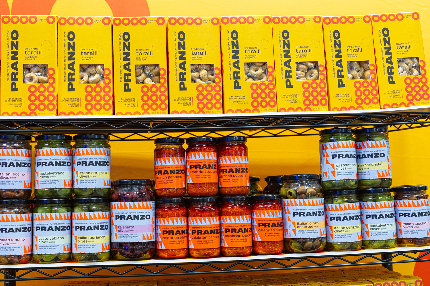 Shelves of Pranzo pasta boxes, pasta jars and sauces in yellow and orange packaging