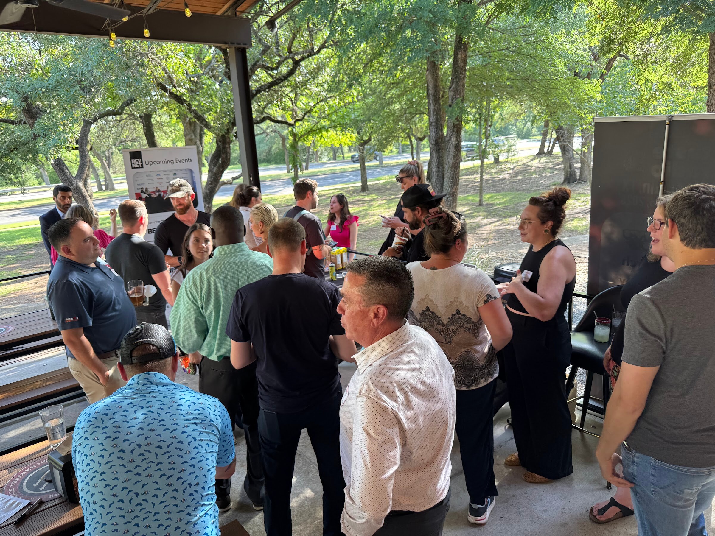 Several attendees in conversation on an outdoor patio, some holding drinks.