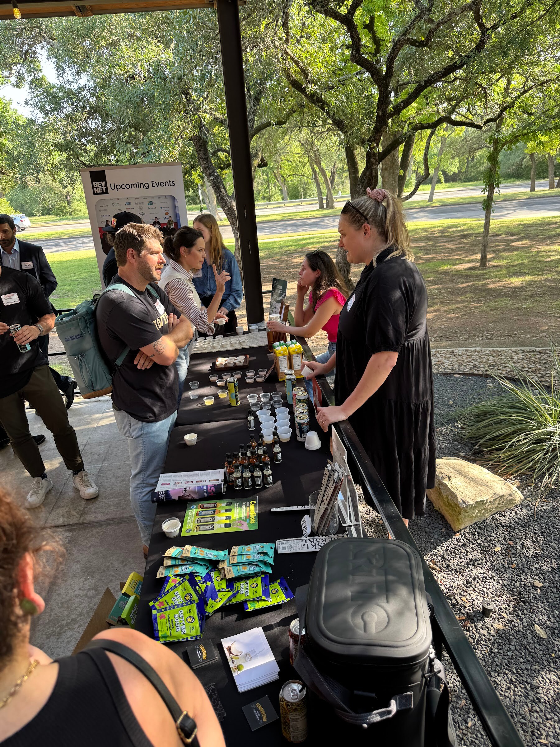 People standing behind a table of product samples on an outdoor patio.