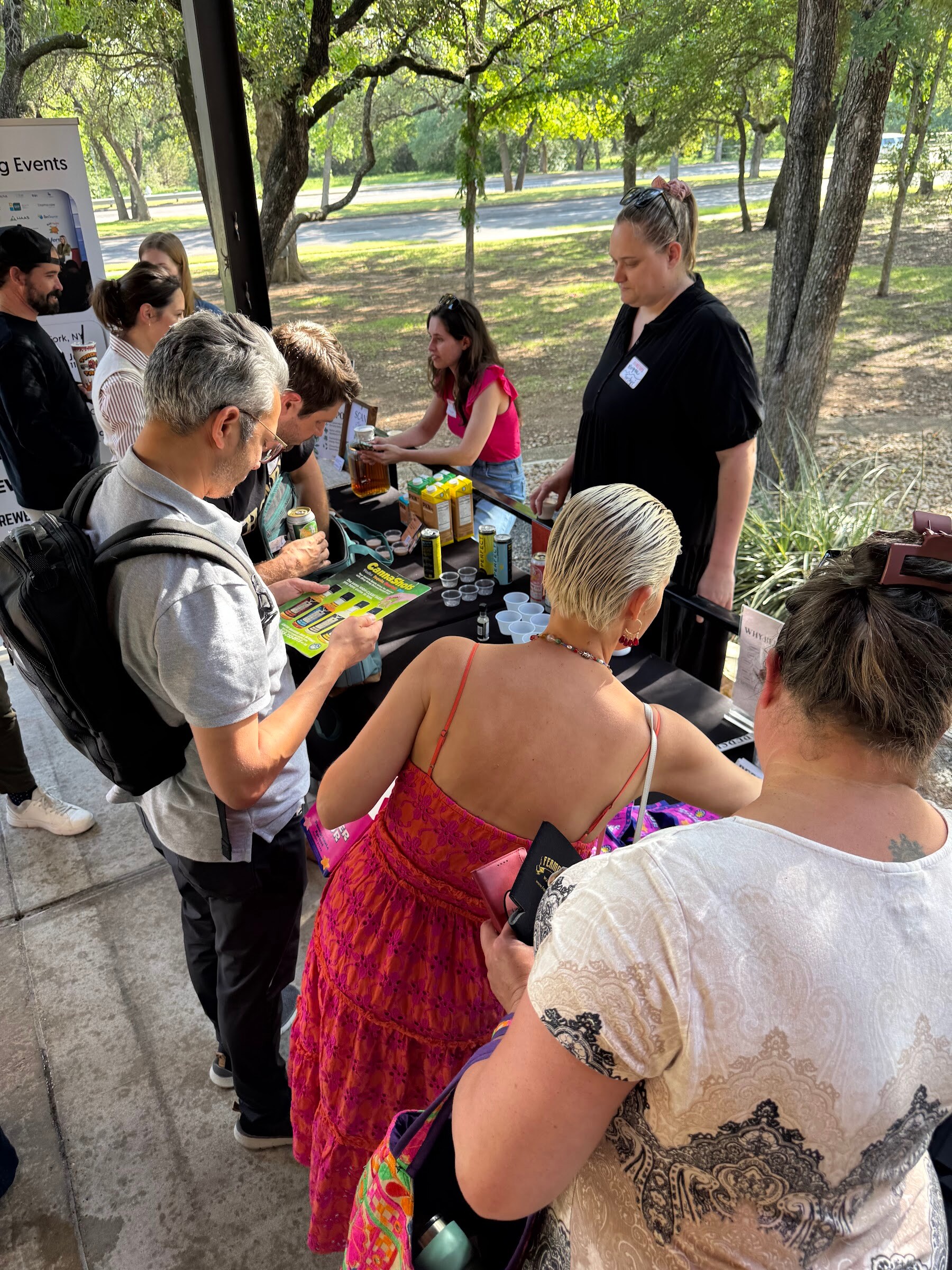 Attendees talking at a patio table, one woman in a red dress in the foreground.