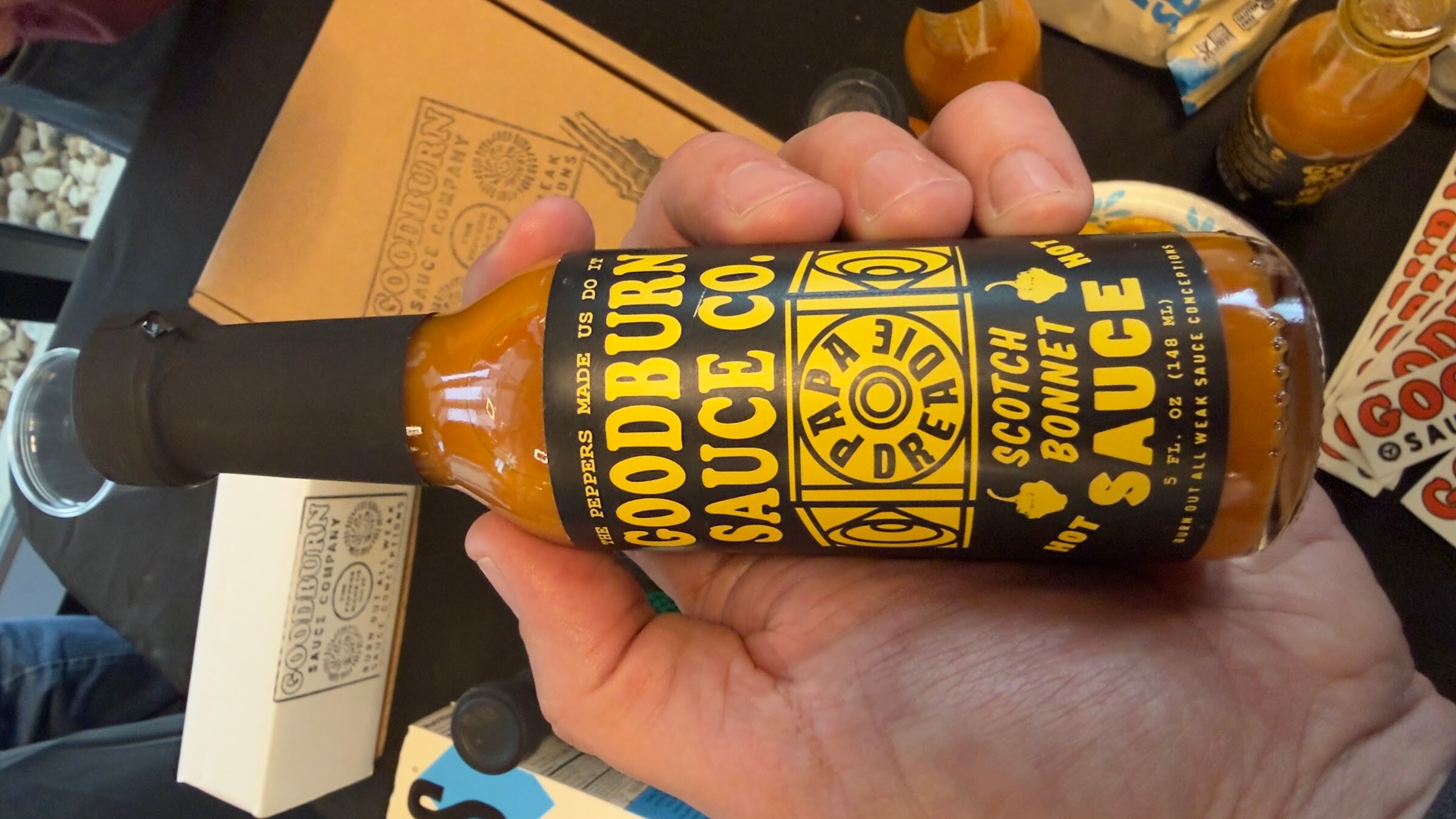 Hand holding a bottle of Goodburn Sauce Co. Scotch bonnet hot sauce.