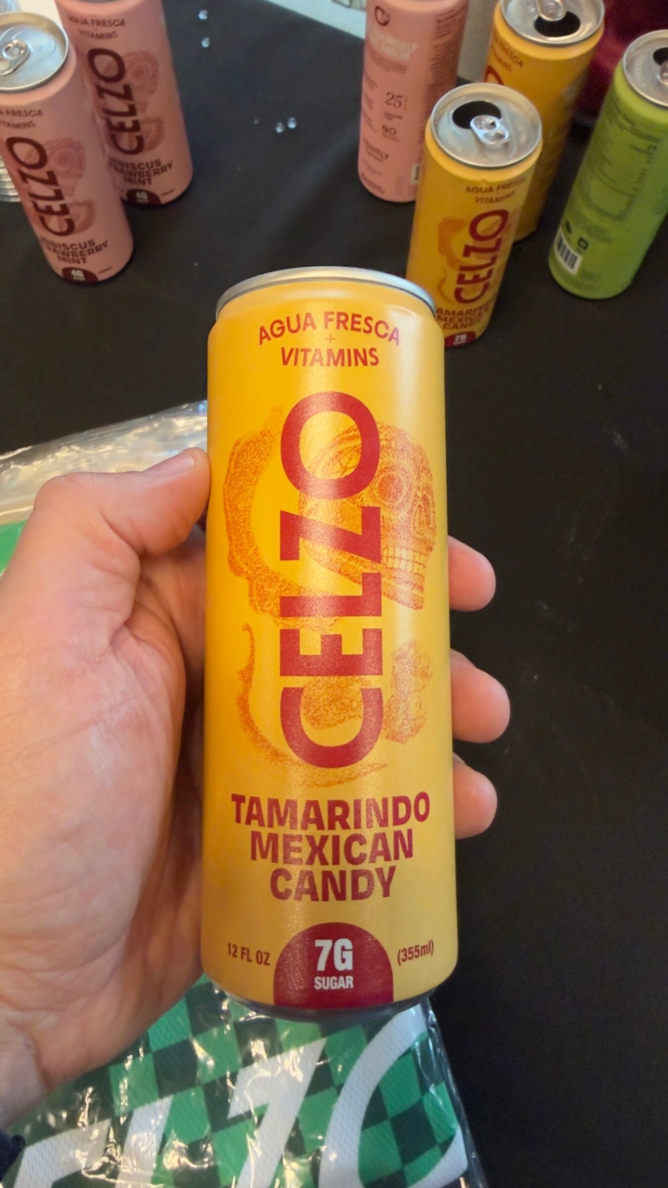 Hand holding a yellow can of Celzo Tamarindo Mexican Candy above more Celzo cans.