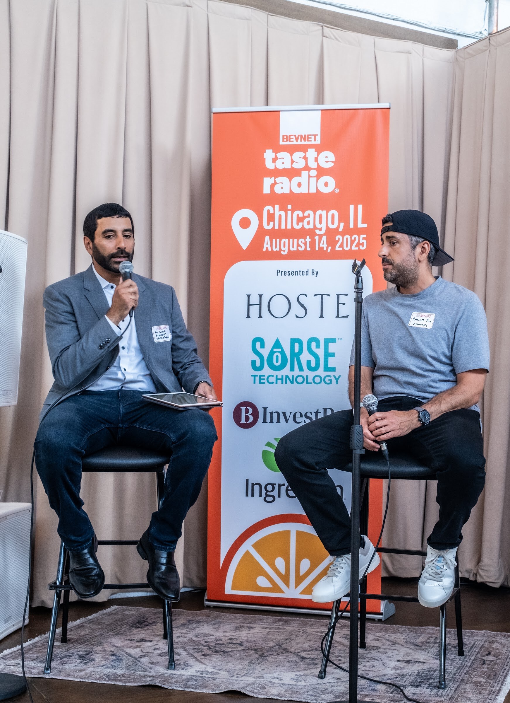 Two men seated on stools in front of a banner listing Hoste, Sorse Technology, InvestBev and Ingredion.