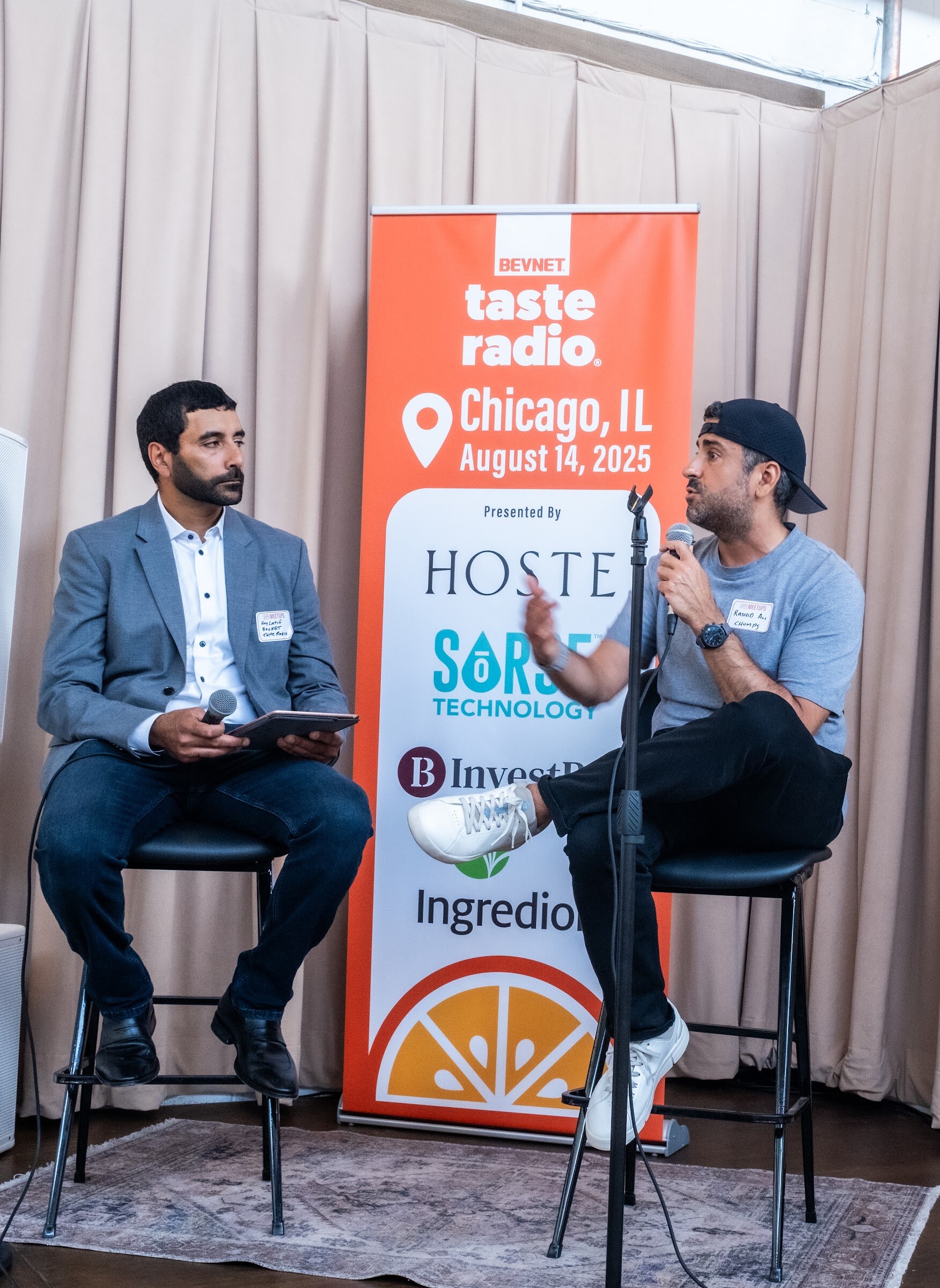 Two men on stools on a small stage beside the Taste Radio Chicago banner.