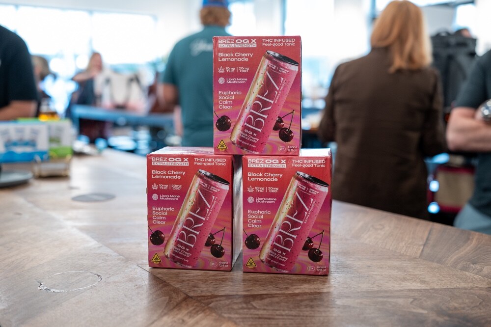 Stacked pink cases of BREZ Black Cherry Lemonade on a wooden bar.