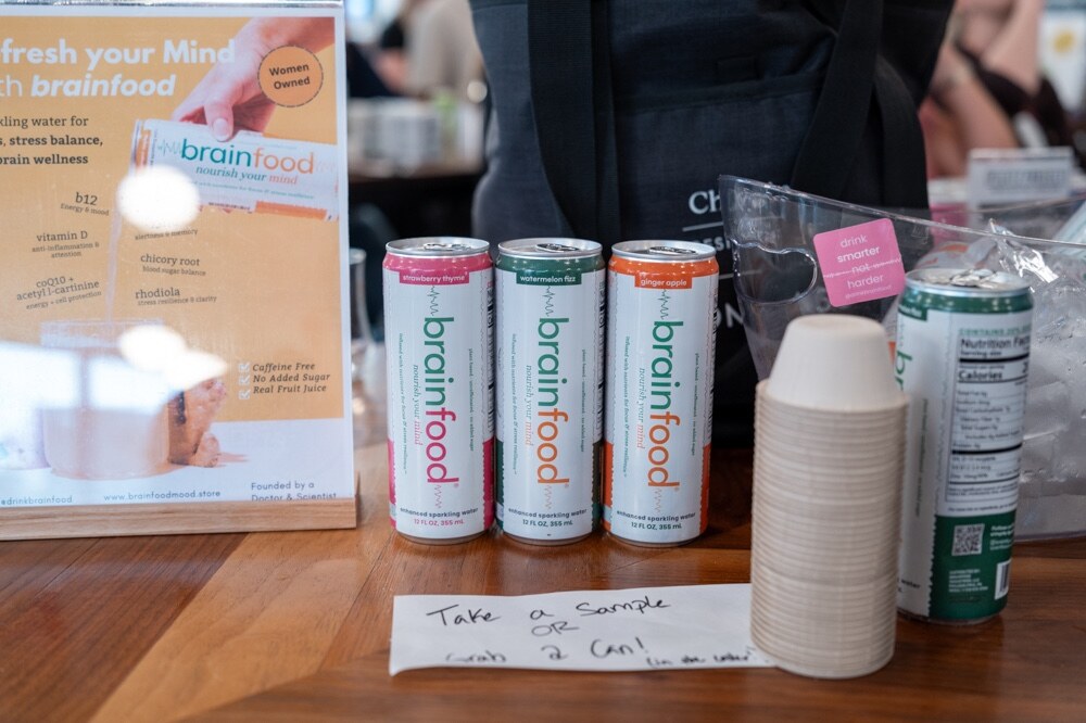Three cans of Brainfood beside sample cups and a sign reading Refresh your mind with brainfood.