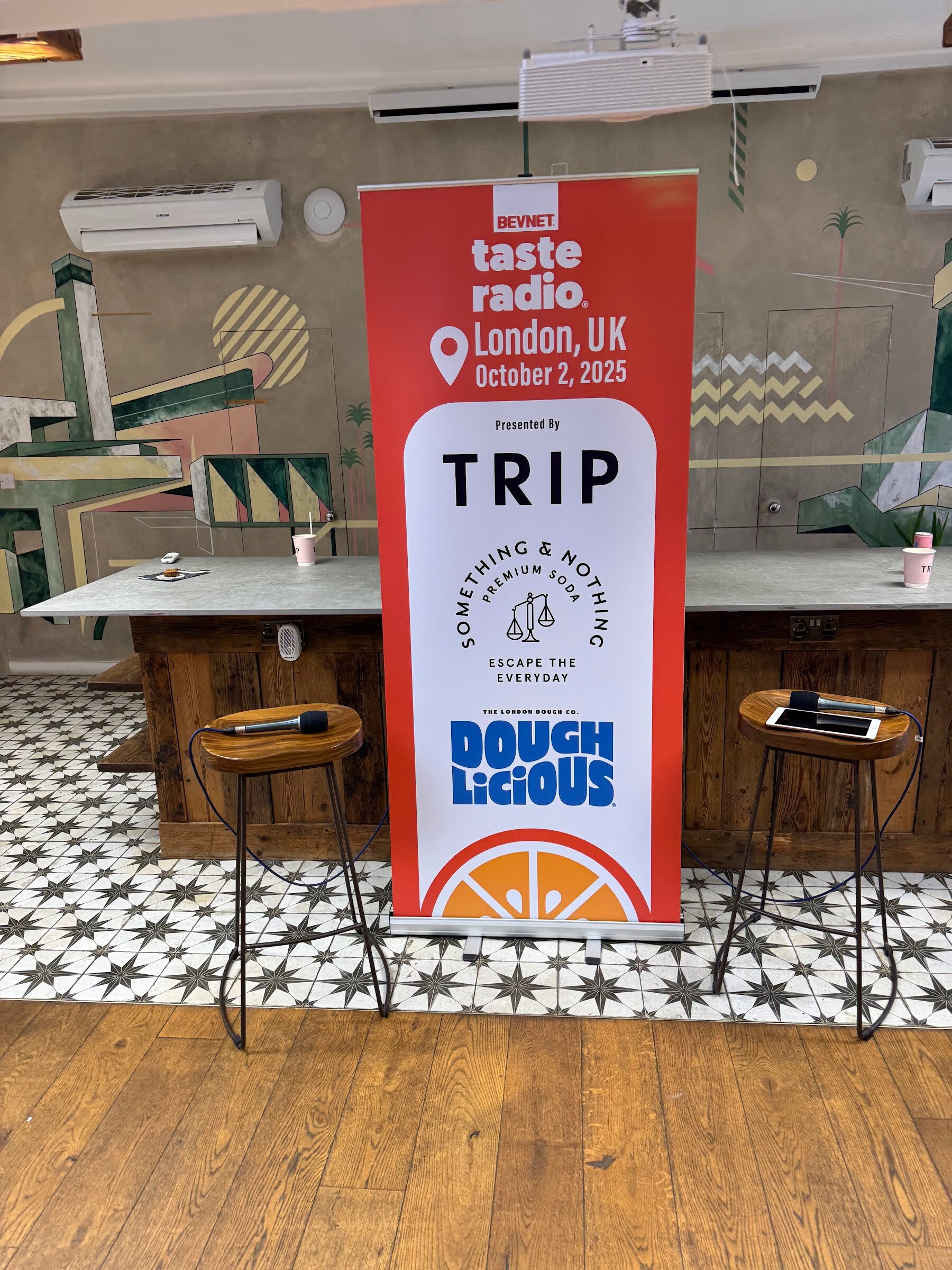 Orange Taste Radio London banner listing TRIP and Doughlicious, with two stools in front.