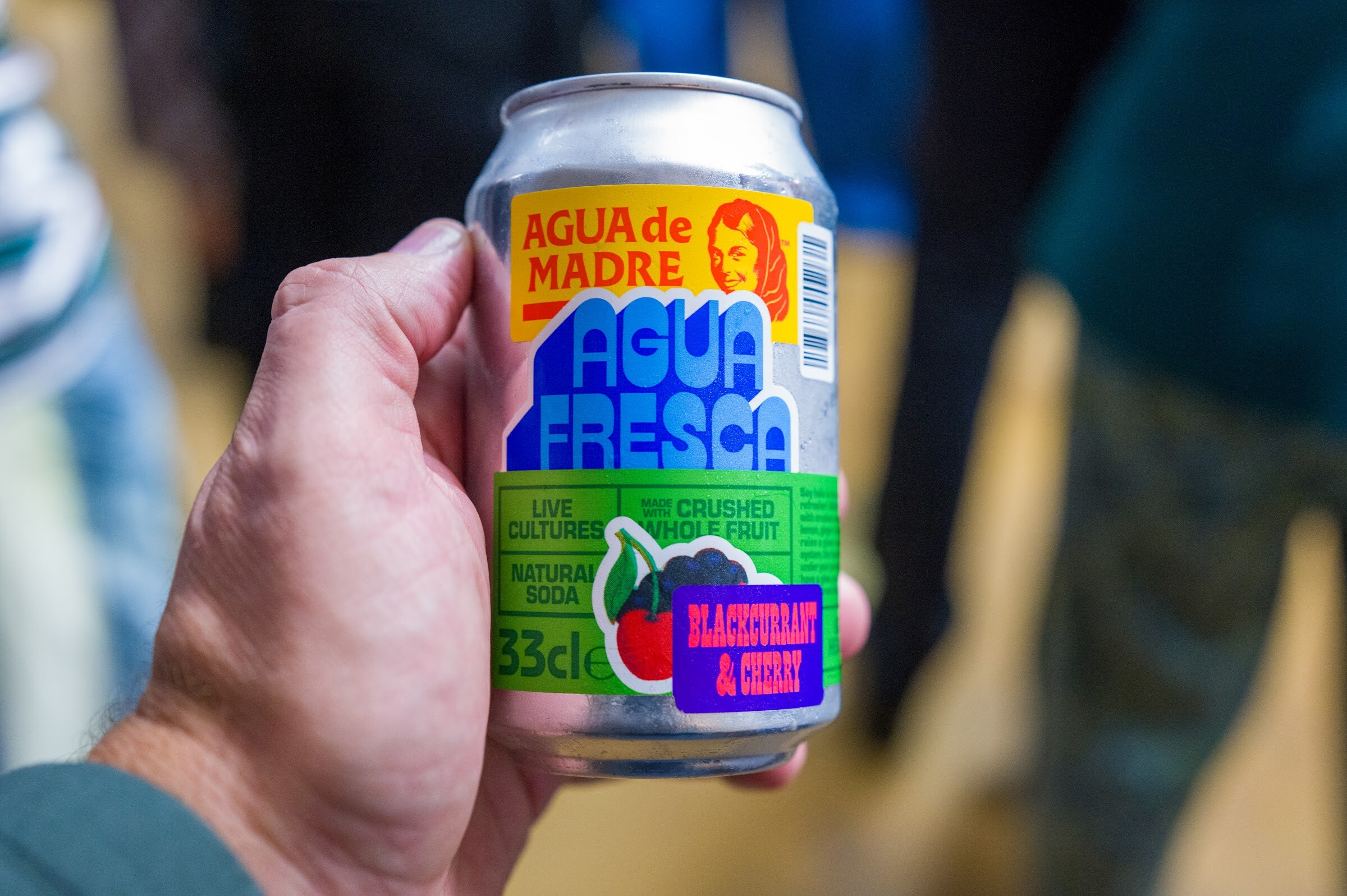 Hand holding a can of Agua de Madre Agua Fresca, blackcurrant and cherry.