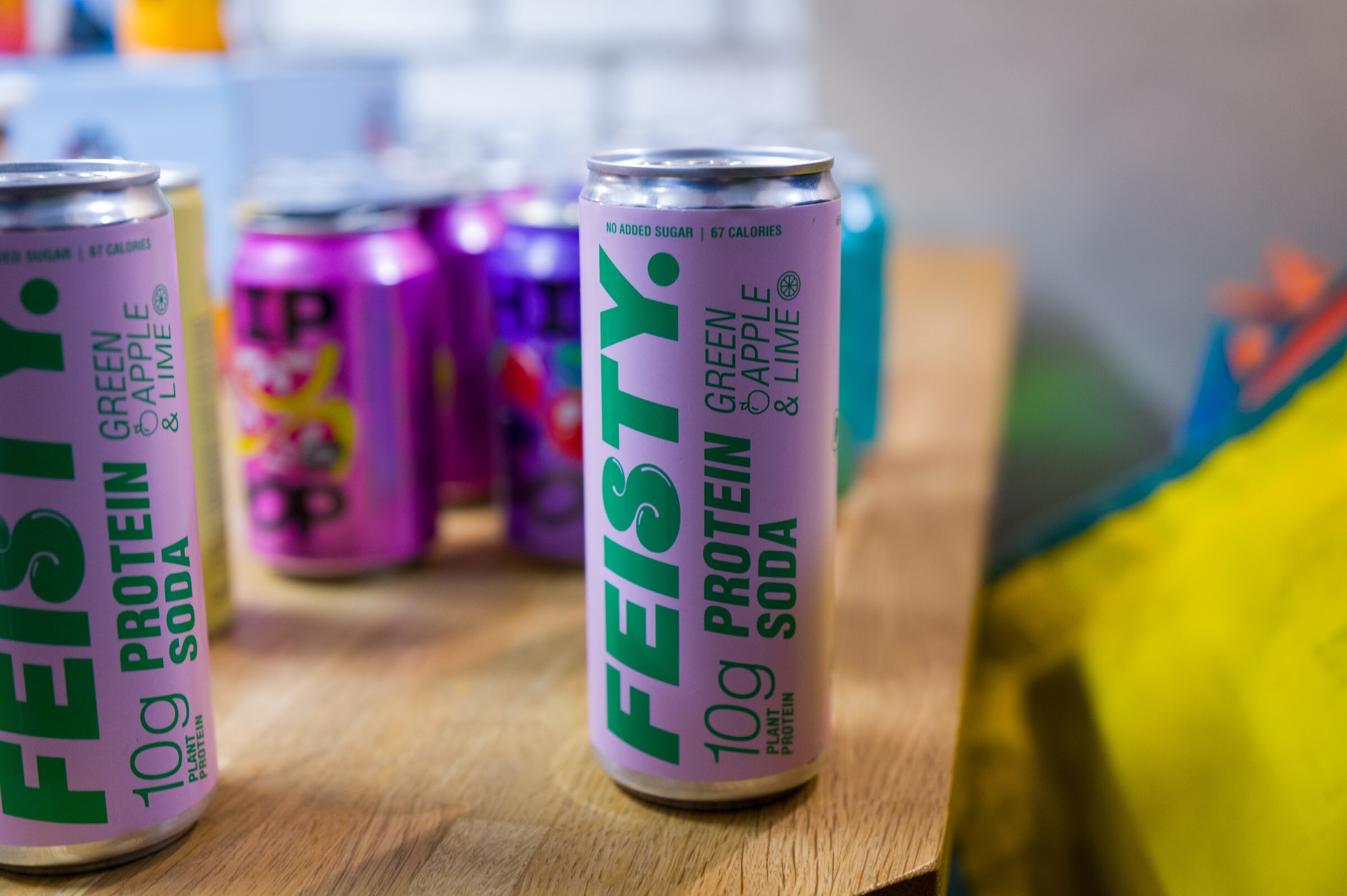 Cans of Feisty protein soda next to purple Hip Pop cans.