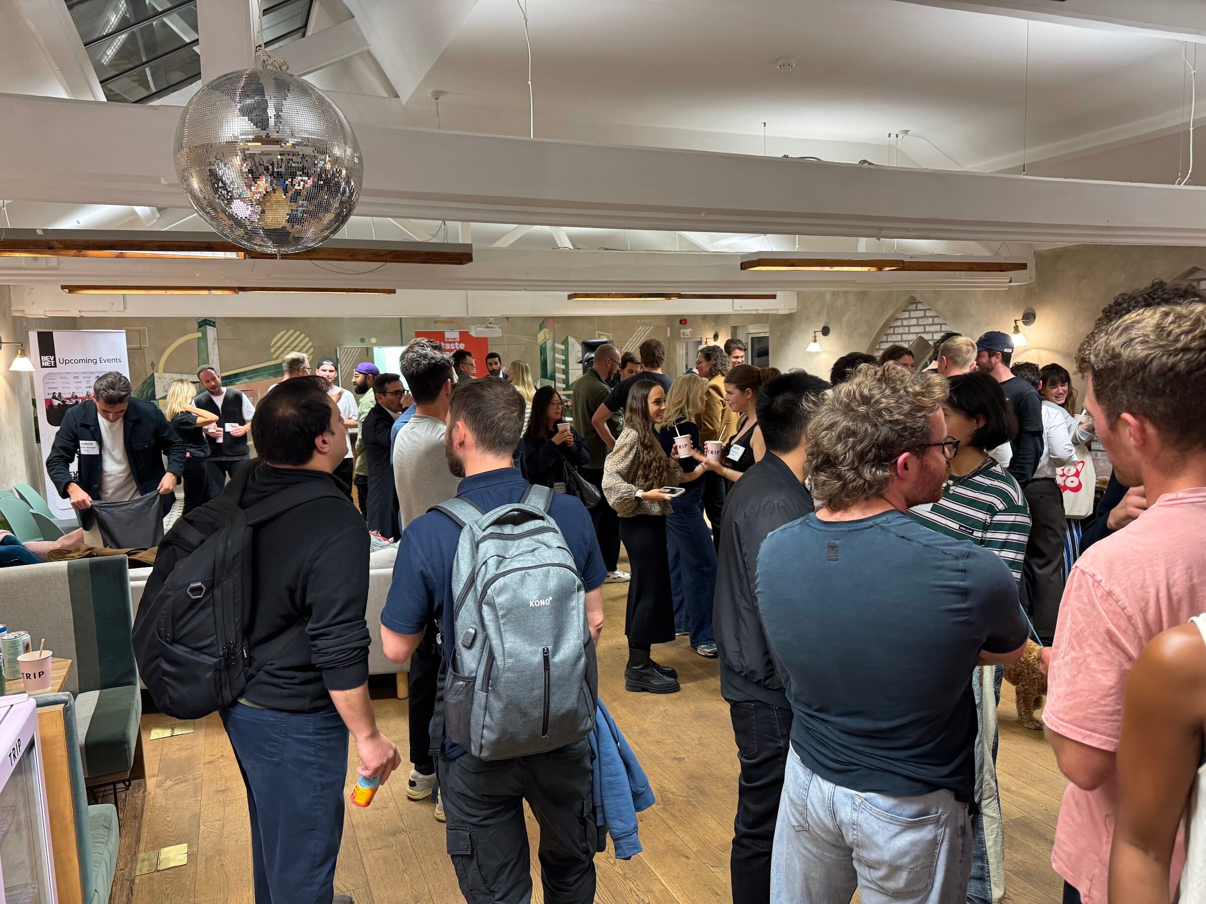 Crowd of attendees in a bright room with a disco ball overhead.
