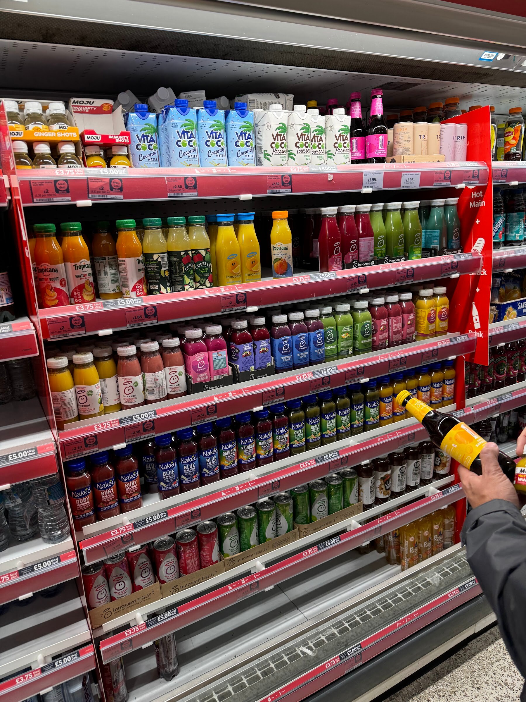Refrigerated shelves full of bottled juices and drinks in a London store.