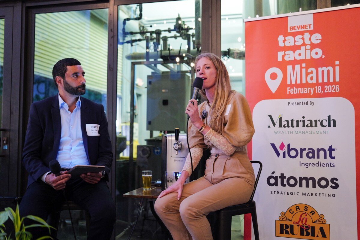 Woman in a tan outfit speaks into a microphone next to the host, beside the Taste Radio Miami February 18, 2026 banner.