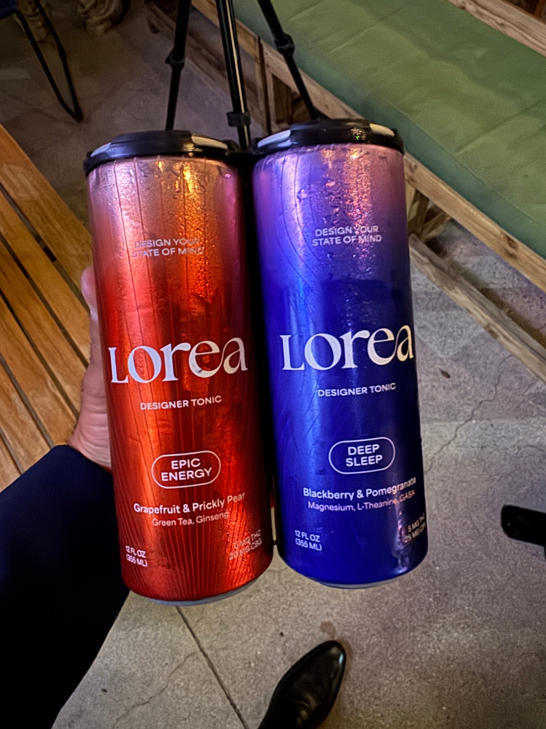 Hand holding orange and blue cans of Lorea designer tonic.
