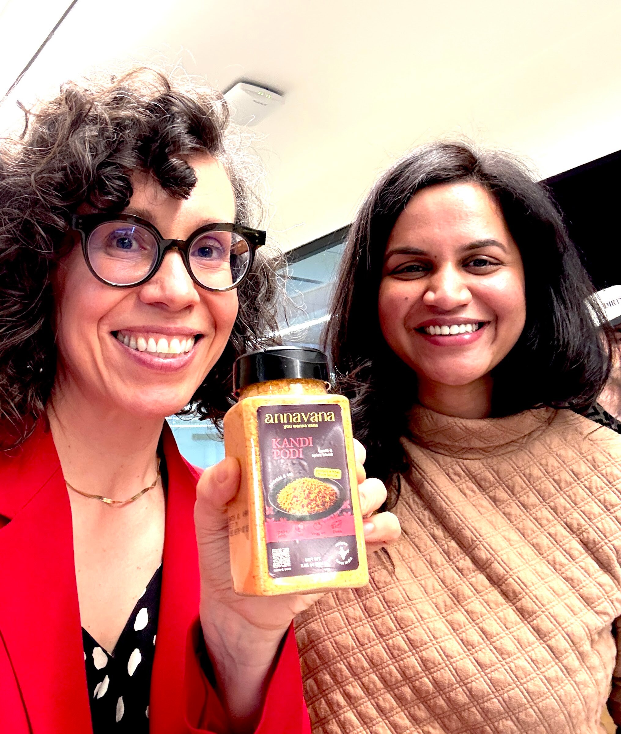 Two smiling women take a selfie holding a jar of Annavana Kandi Podi.