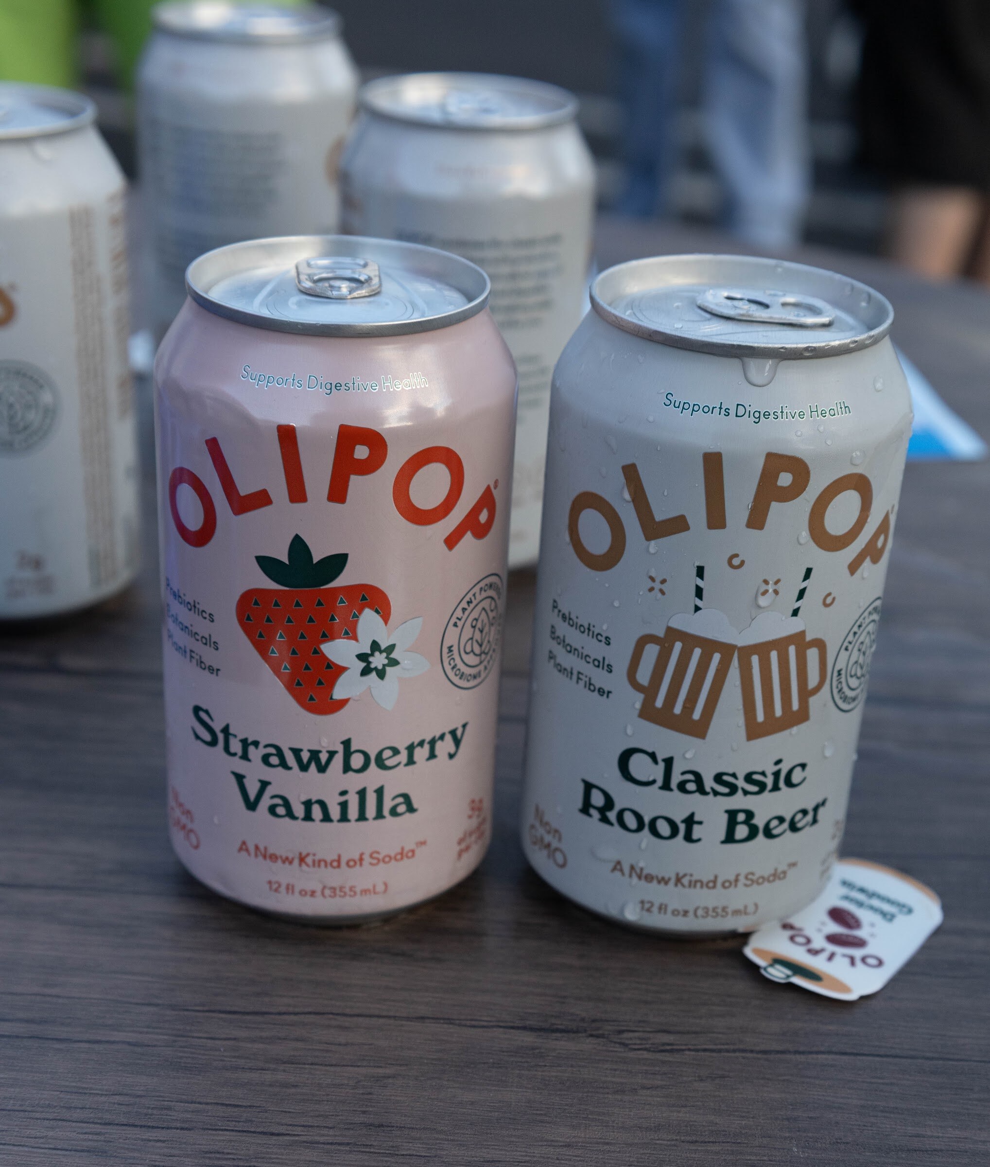 Two Olipop cans on a wooden table.