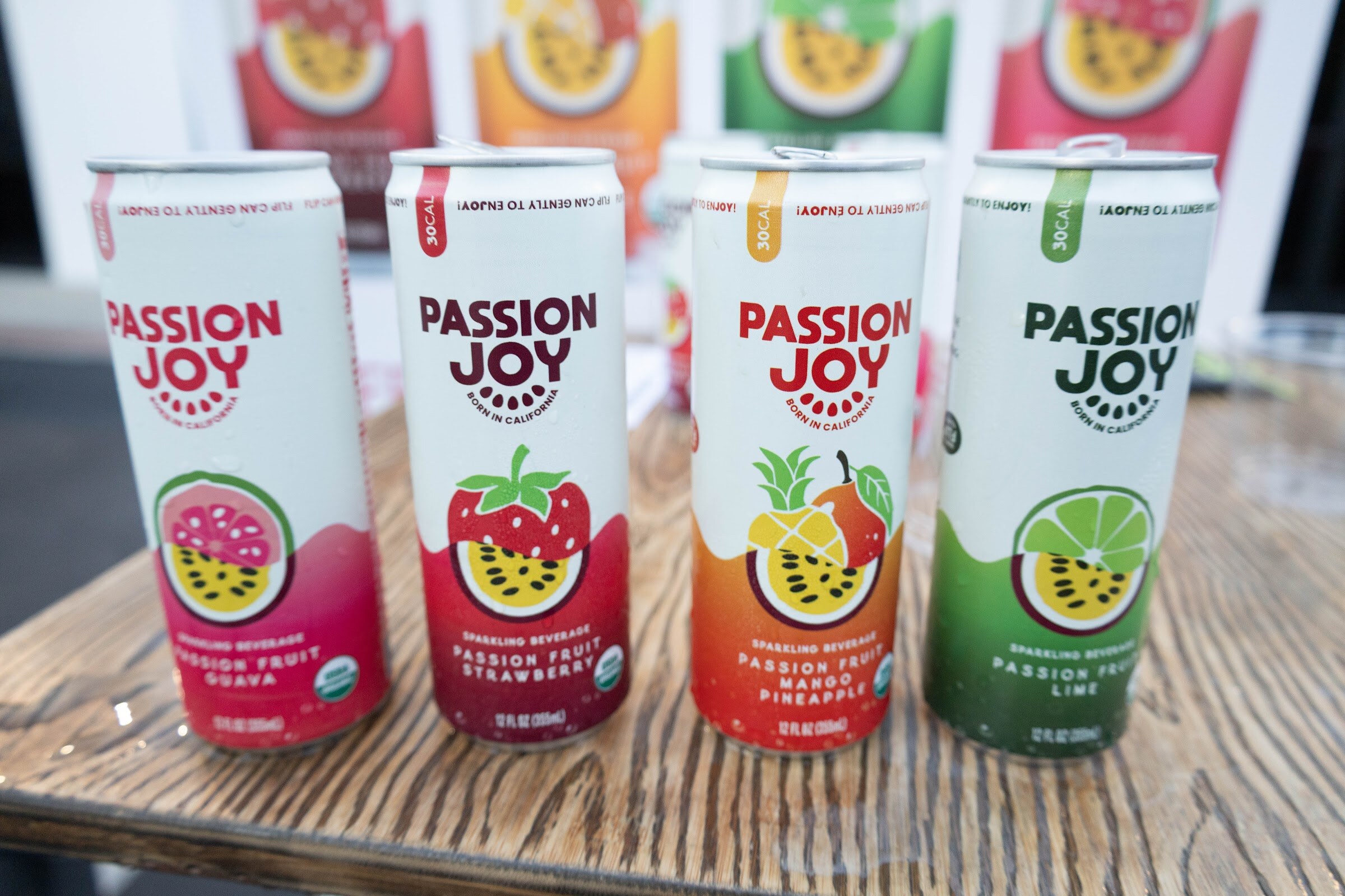 Four Passion Joy cans on a wooden table.