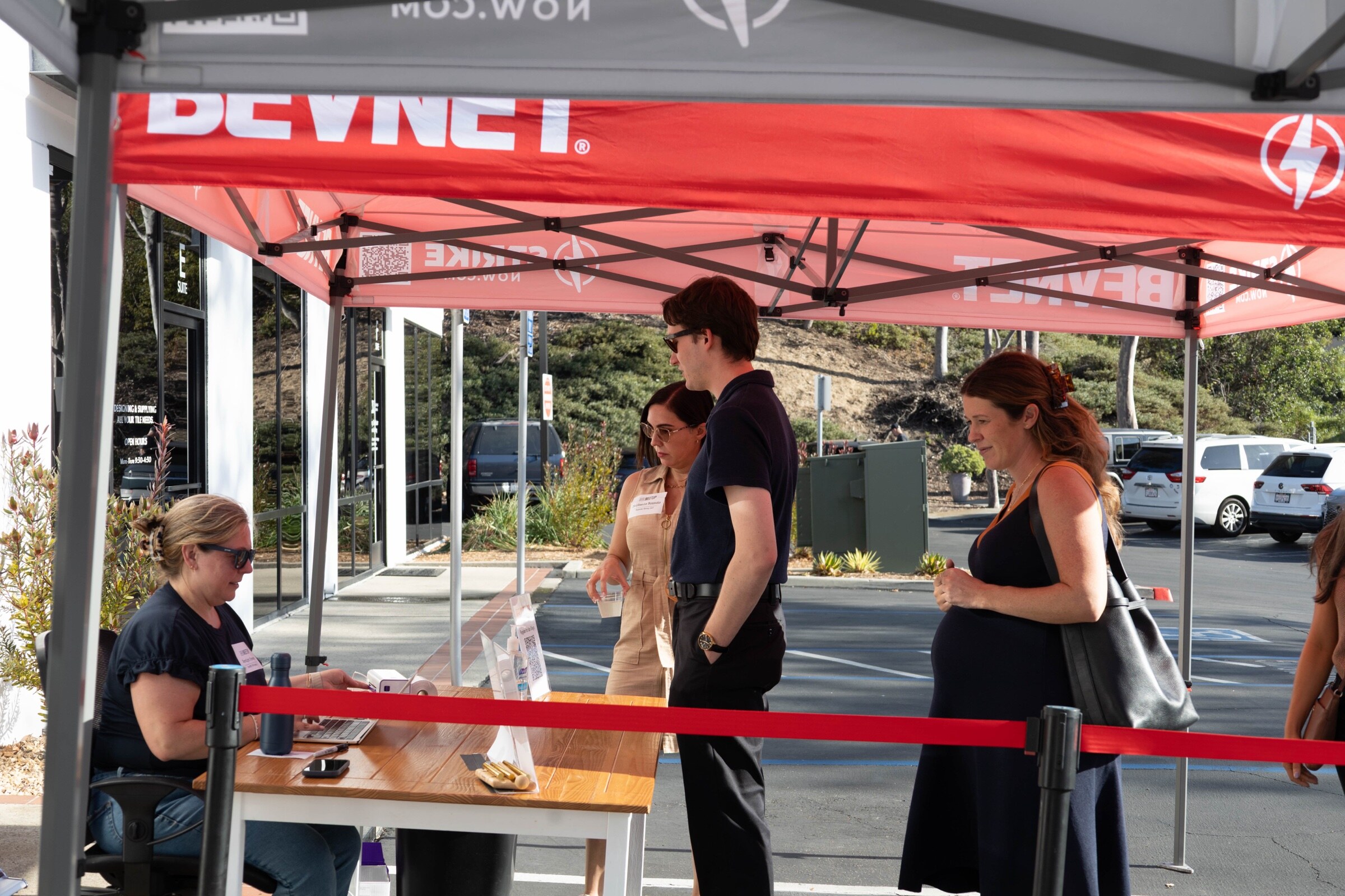 Attendees wait at a check-in table under a red BevNET canopy while a staff member works at a laptop.