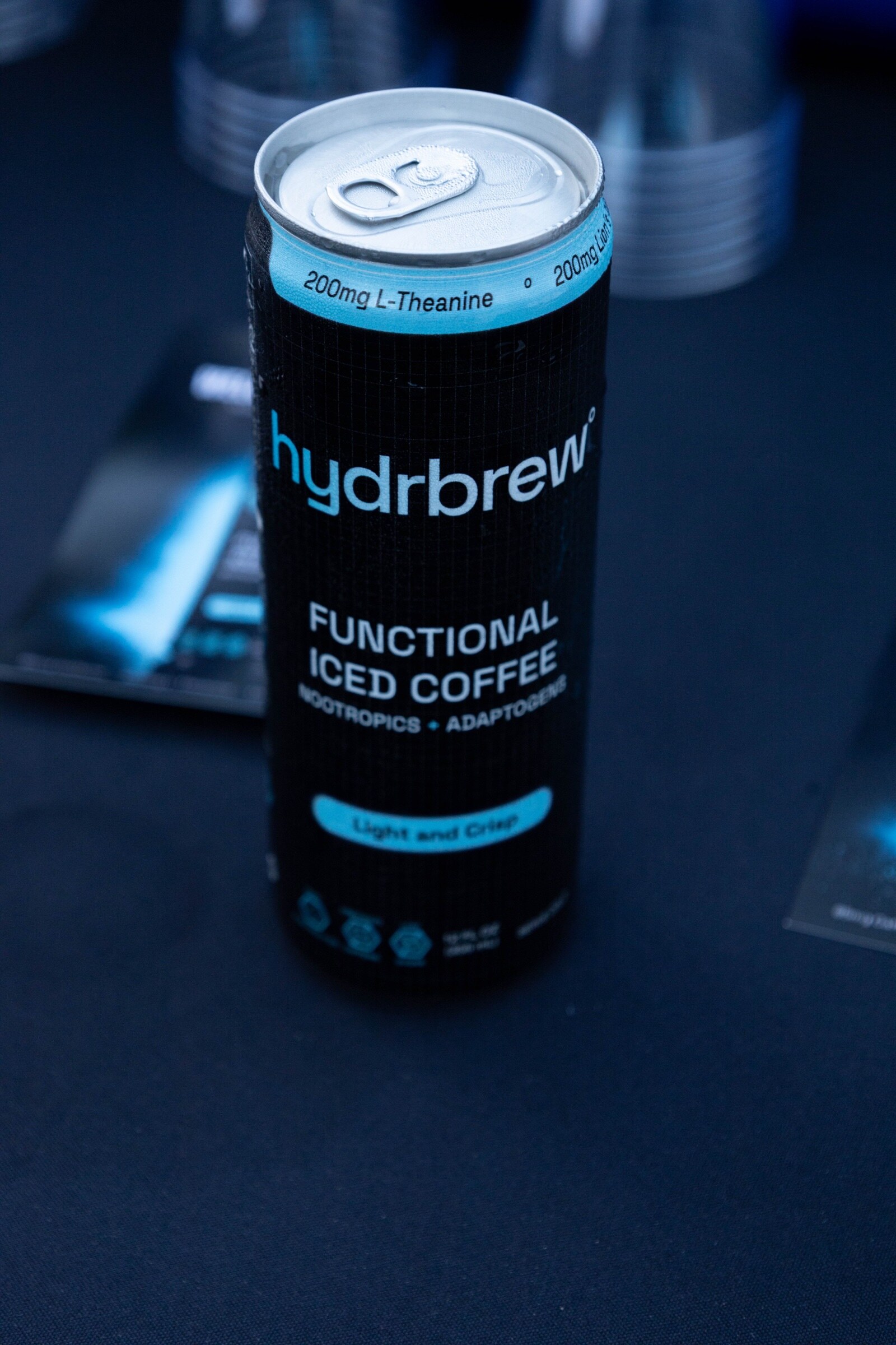 A black can of hydrbrew Functional Iced Coffee, Light and Crisp, on a dark tablecloth.